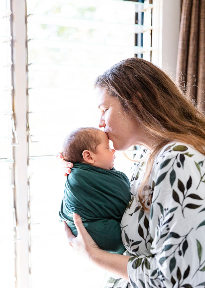 middle georgia newborn photographer. Newborn family lifestyle photo shoot. forehead kiss mother and newborn